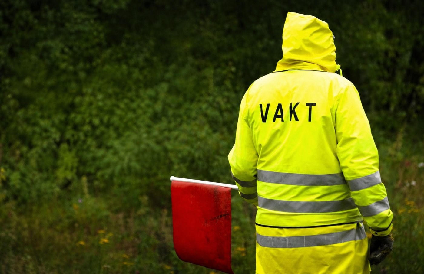 Flaggvakt i varselkläder leder trafiken förbi ett vägarbete i Stockholm